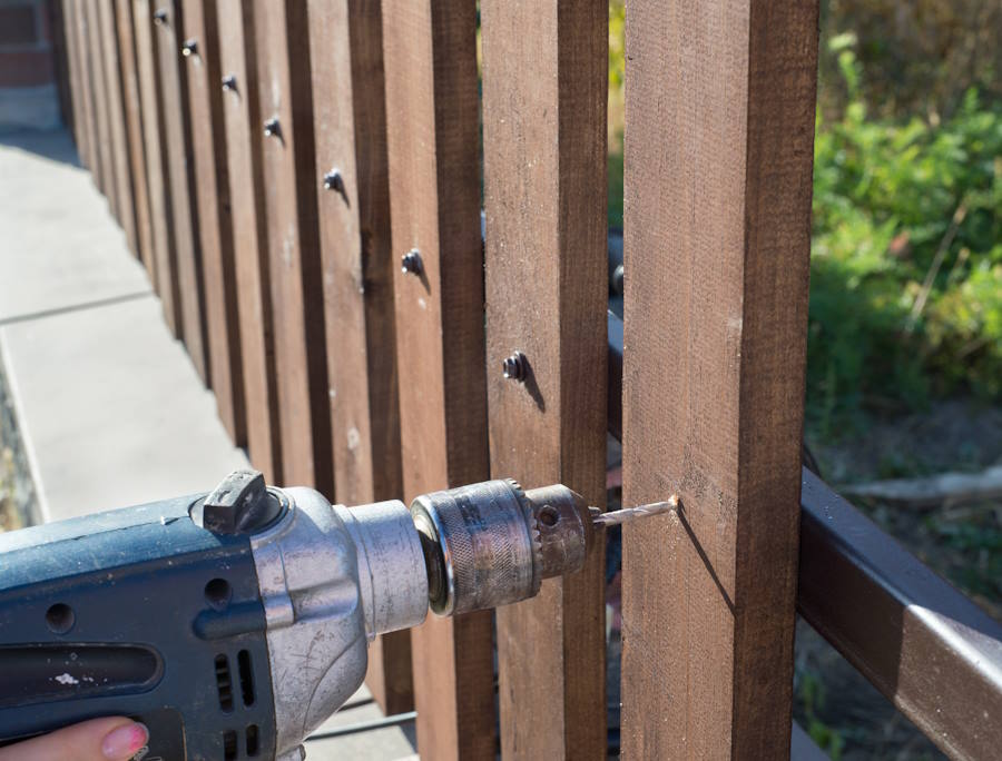 woman-hands-drilling-wood-plank-fence-metal-construction-building-wooden-fence-with-drill-screw